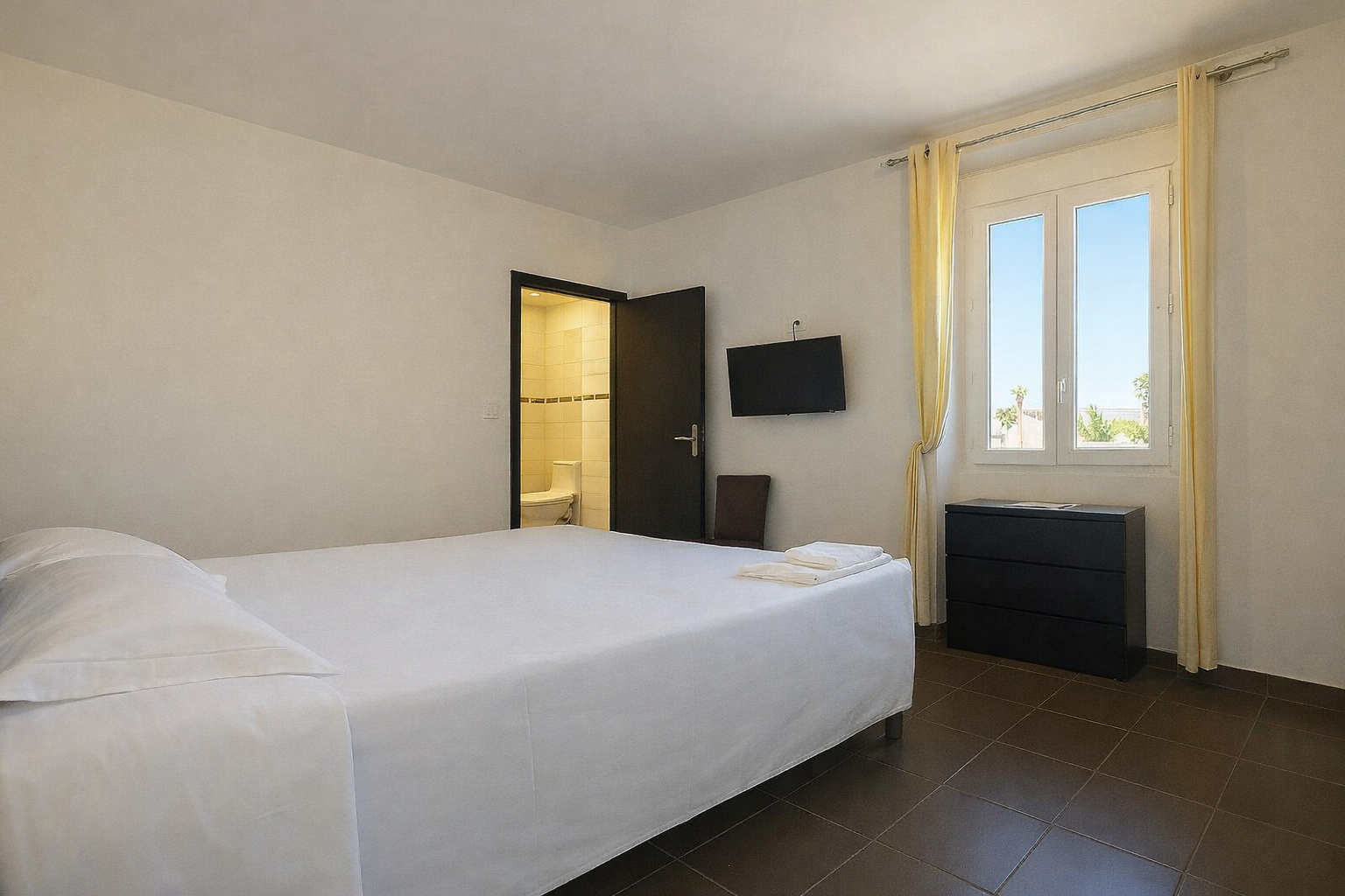 Chambre vue mer à La Croix Valmer avec lit double, fenêtre lumineuse et salle de bain ouverte à l’hôtel La Cigale