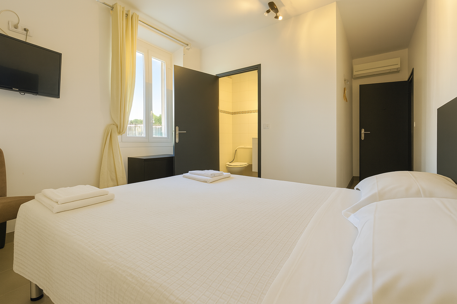 Chambre vue mer à La Croix Valmer avec lit double, télévision murale et salle de bain à l’hôtel La Cigale