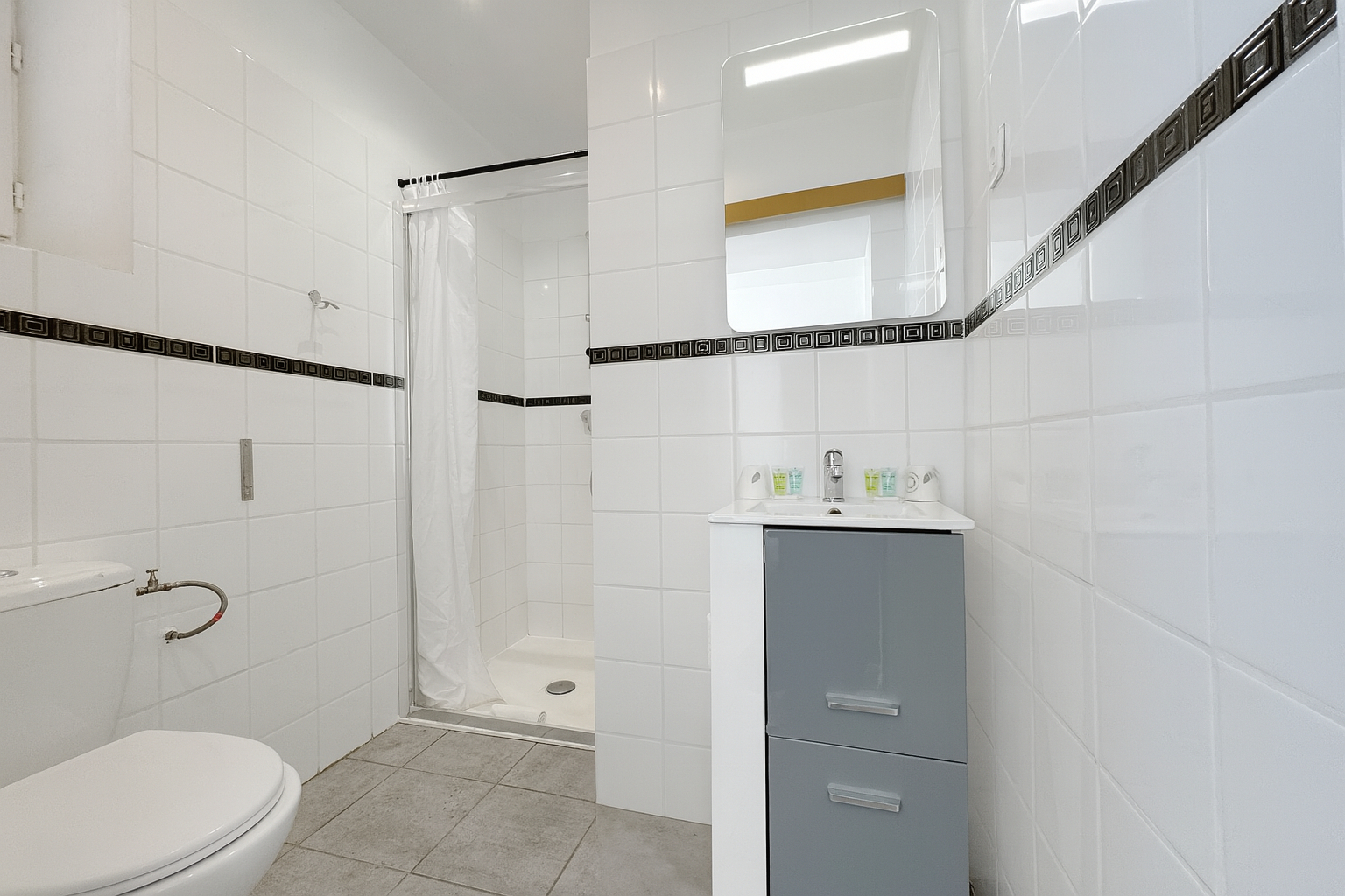 Salle de bain avec douche dans une chambre vue rue à l’hôtel La Cigale